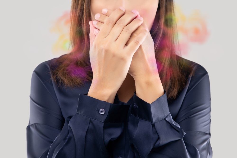 A,woman,covers,her,mouth,,struggling,with,halitosis,and,bad